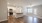 Kitchen and dining area at Sanctuary at Powell Place in Pittsboro, NC, featuring wood-look flooring, plush carpet in the living area, kitchen island, and access to a private balcony with natural light from large windows.