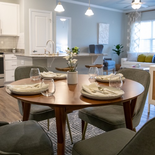 Well lit dining area with a view of the kitchen and living room